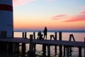 Lighthouse pier with stroller walking woman silhouette on sunset sky background Royalty Free Stock Photo