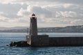 Lighthouse in the port, seascape. Beacon, sea, and clouds at sunset, Nice, France Royalty Free Stock Photo