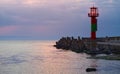 Lighthouse protected by concrete breakwater tetrapods at sunset Royalty Free Stock Photo