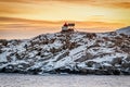 Lighthouse with red roof on top of snow-capped mountain. Royalty Free Stock Photo