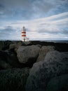 Lighthouse with red stripes wide angle over the black rocks Royalty Free Stock Photo