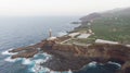Lighthouse in a rocky cliff and banana tree around on the atlantic ocean. Coastline in the sunset. Light orientation to navigate