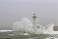 Lighthouse in rough seas with crashing waves.