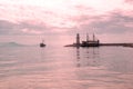 Lighthouse and sail ships in the Mediterranean sea at sunset