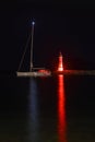 lighthouse and sailboat at dusk. With reflections in the water. Royalty Free Stock Photo