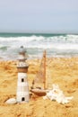 Lighthouse, sailboat on sea sand and ocean horizon.