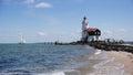 Lighthouse and sailing boat in sunny landscape