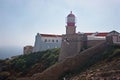 Lighthouse at Sant Vincent cape, with a seagull flying in front Royalty Free Stock Photo