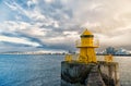 Lighthouse on sea pier in reykjavik iceland. Lighthouse yellow bright tower at sea shore. Sea port navigation concept Royalty Free Stock Photo