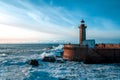 The waves of the Atlantic Ocean crash against the rocks at sunset by the lighthouse Royalty Free Stock Photo