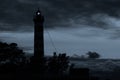 Lighthouse shines in the dark with a dramatic sky. silhouette of glowing beacon in darkness Royalty Free Stock Photo