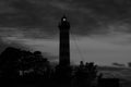 Lighthouse shines in the dark with a dramatic sky. silhouette of glowing beacon in darkness Royalty Free Stock Photo