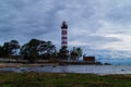 Lighthouse shines near the shore at sunset Royalty Free Stock Photo