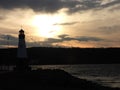 Lighthouse silhouette on lake with setting sunset clouds Royalty Free Stock Photo