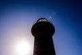 A lighthouse is silhouetted against a blue sky Royalty Free Stock Photo