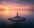 Lighthouse on smal island in the sea at colorful sunset in summer Royalty Free Stock Photo