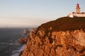 Lighthouse standing on the hige rock in front of ocean coast in the sunset light.