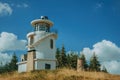 Lighthouse on top of hill covered by grass and trees Royalty Free Stock Photo