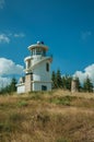 Lighthouse on top of hill covered by grass and trees Royalty Free Stock Photo