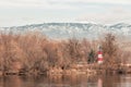 Lighthouse in the trees with snow capped mountains in the background Royalty Free Stock Photo