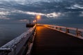 Lighthouse on the wooden bridge against a clouded sky Royalty Free Stock Photo