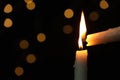 Lighting candle from another one against blurred lights in darkness, closeup. Space for text Royalty Free Stock Photo