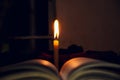 The lighting candle through the open book. Education is the light of a nation. Candle light reflection on the book