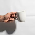 Lighting creates a soft shadow, emphasizing the mug\'s curves and the hand\'s Royalty Free Stock Photo