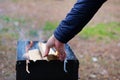 Lighting the grill. Man kindles fire for grilling. Man's hand is adding wood into fire Royalty Free Stock Photo