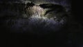 Lighting a flashlight in dark cave, exploring, looking up at stalactites