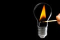 Lighting a light bulb with a match on black Royalty Free Stock Photo