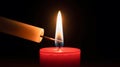 Lighting a red candle with a match in a dark setting close up view Royalty Free Stock Photo