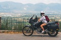 A lightly dressed girl is sitting on a motorcycle. No protection. Helmet. Sunny day in Narni, Italy. Green mountains in the