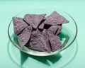 Lightly Salted Organic Blue Corn Tortilla Chips in clear glass bowl isolated on green Royalty Free Stock Photo
