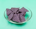 Lightly Salted Organic Blue Corn Tortilla Chips in clear glass bowl isolated on green Royalty Free Stock Photo