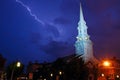 A lightning bolt flashes across the sky near a historic church