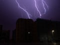 Lightning bolts light up sky in city during storm at night. Royalty Free Stock Photo