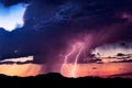 Lightning bolts strike from a storm at sunset.