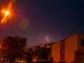 Lightning over city houses and beautiful rays of light from street lamps - long exposure at night Royalty Free Stock Photo