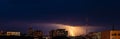 Lightning over city. Panoramic dramatic view. Thunderstorm and dark storm clouds over buildings