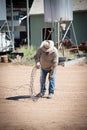 Farmer rolls a length of barbed wire with leather gloves on the property