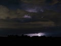 Lightning shoots toward Earth at night from a distant thunderstorm cloud