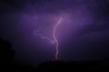 A very branching lightning flashes above the roofs of city houses in a summer thunderstorm. Royalty Free Stock Photo