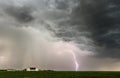 Lightning strikes field near farm under storm clouds Royalty Free Stock Photo