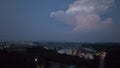 Lightning strikes in towering cumulous cloud over town lights at night