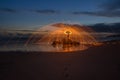 Lightpainted orb with flying sparks on a beach with a warm sunset in the background