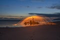 Lightpainted orb with flying sparks on a beach with a warm sunset in the background