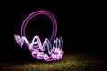 Lightpainting effect with purple circle and waves, created with bulb exposure. green grass ground