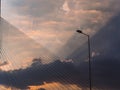 Lightpost and suspension bridge cables with sunbeams bursting through the clouds