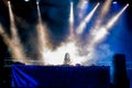 Lights beams on stage and young woman Dj in smoke playing music at Summer Night Festival. Royalty Free Stock Photo